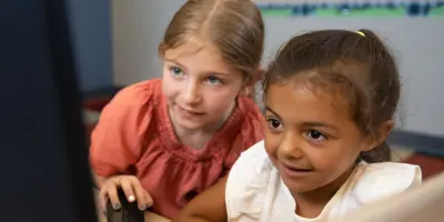 photo of two girls using a computer